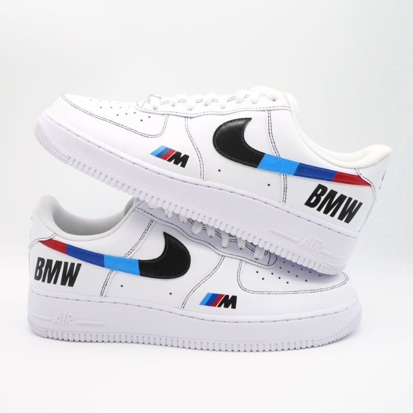 Paar weiße Nike Air Force 1 Custom Sneaker mit BMW M Design, schwarzer Swoosh blau-rot-weiße M-Streifen und BMW-Schriftzug auf den Außenseiten beider Schuhe