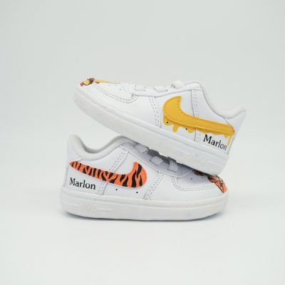 Weiße Air Force 1 Babysneaker mit gelb tropfendem Swoosh, schwarzen Tigerstreifen, kleinem Tiger-Gesicht und personalisiertem 'Marlon' Schriftzug an der Ferse.