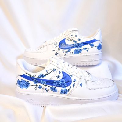 Weiße Nike Air Force 1 Sneakers mit blauen Blumenmustern auf der Seite.