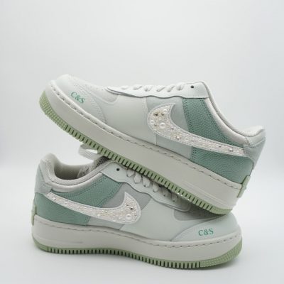 Nike Air Force 1 Sneakers in Eukalyptusfarbe mit weißen Details und glitzernden Applikationen.