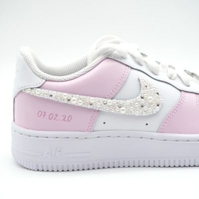 Rosa Nike Air Force 1 Sneakers mit weißen Schnürsenkeln und Perlenverzierung auf dem Swoosh.