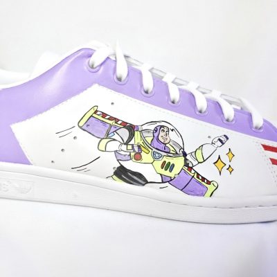 Lila und weiße Schuhe mit einem Buzz Lightyear Motiv auf der Seite.