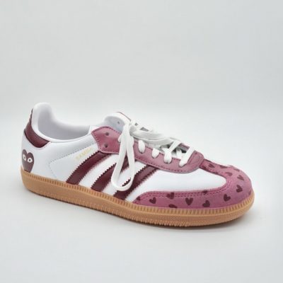 Ein stylischer Sneaker mit weißer Sohle, kastanienbraunen Streifen und hellbrauner Sohle. Spitze und Ferse sind mit kastanienbraunen Herzmustern verziert, und an der Ferse befindet sich eine verspielte Augengrafik. Der Schuh hat weiße Schnürsenkel und einen goldenen SAMBA-Schriftzug.