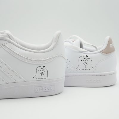 weiße Sneaker mit kleinen Geister Motiven auf der Seite. Die Geister sind eng umschlungen und haben ein Herz über sich.