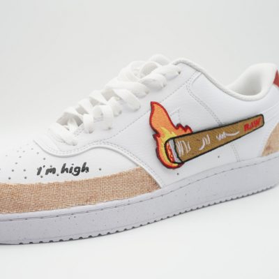weiße Sneaker mit Raw Paper Motiv Stickern.