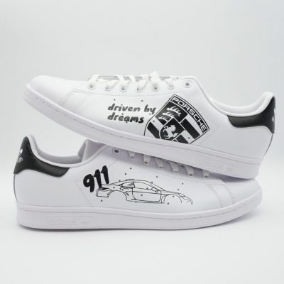 Weißer Sneaker mit einem einem Porsche Auto auf der einen Seite und dem Porsche Logo auf der anderen Seite. Dazu der Spruch drinnen by dreams und 911