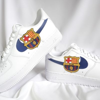 Weiße Sneakers mit blauen Akzenten und dem FC Barcelona Wappen auf der Seite.