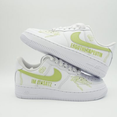 Weißer Nike Air Force 1 Sneaker für Ergotherapeutin mit hellgrünem Swoosh, dezenten Logos und seitlichen Aufschriften 'Ergotherapeutin' und 'Im Einsatz' in grüner Schrift.