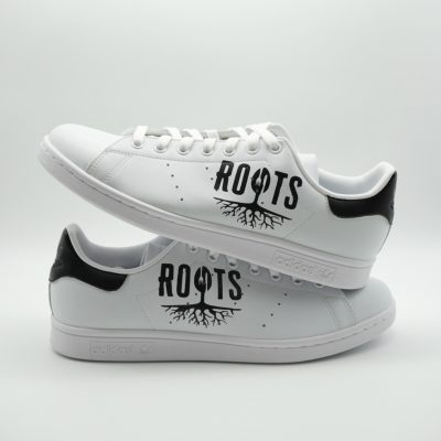 Weiße Adidas Stan Smith Sneaker mit handgemaltem schwarzem Baum-Motiv samt Wurzelwerk und Schriftzug 'Roots' auf den Seitenflächen im klassischen Look.