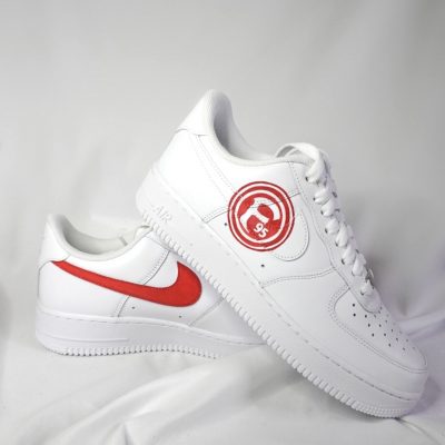 Weiße Nike Air Force 1 Sneakers mit rotem Logo und rotem Nike-Swoosh auf der Seite.