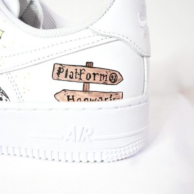 Weiße Sneakers mit handgemaltem Wegweiser zu Plattform 9¾ und Hogwarts.