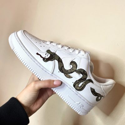 Weiße Sneakers mit einem Schlangendesign auf der Seite, inspiriert von Slytherin aus Harry Potter.