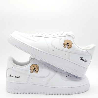 Zwei gestapelte weiße Nike Air Force 1 mit Golden Retriever Welpen Porträts und personalisierten Namens-Schriftzügen 'Ronja' und 'Amadeus' in schwarzer Schreibschrift.