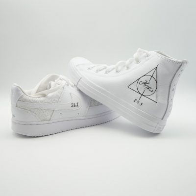 Zwei Converse Chuck Taylor in Weiß, ein Low- und ein High-Top, mit dezentem Heiligtümer-des-Todes Symbol und 'L & S' bzw. 'S & L' im minimalistischen Look.