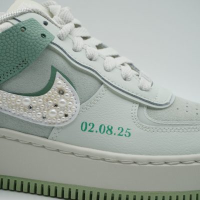 Nahaufnahme eines mintgrünen Nike Air Force 1 Shadow mit doppeltem Swoosh, einer Hälfte aus weißen Perlen, grüner Datumsangabe '02.08.25' und Plateausohle.