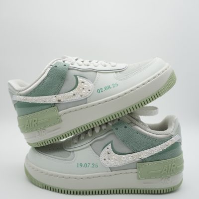 Zwei gestapelte mintgrüne Nike Air Force 1 Shadow Sneaker mit perlenbesetztem Swoosh, grünem Akzent und Datumsangaben '02.08.25' und '19.07.25' an den Seiten.