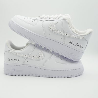 Zwei gestapelte weiße Nike Air Force 1 mit perlen- und glitzersteine-besetztem Swoosh, dezenten Punkten und 'Mrs. Fischer' Schriftzug sowie Datum '06.12.2025'.