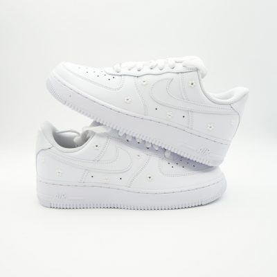 Zwei gestapelte weiße Nike Air Force 1 mit kleinen verteilten Perlenblumen in zarter Anordnung auf den Seiten im minimalistischen Braut-Sneaker Design.
