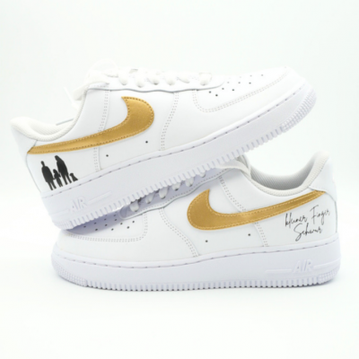 Weißer Nike Air Force 1 Sneaker mit goldenem Swoosh, schwarzer Familien-Silhouette und handschriftlicher Personalisierung 'kleiner Finger Schwur' an der Ferse.
