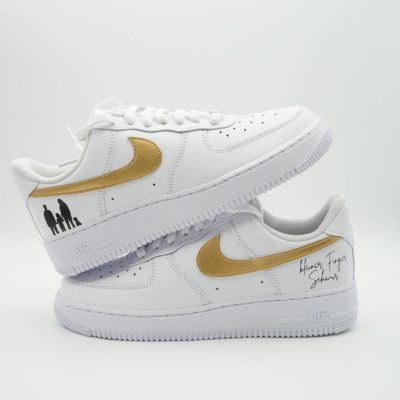 Weißer Nike Air Force 1 mit goldenem Swoosh, schwarzer Familien-Silhouette an der Ferse und handschriftlicher Aufschrift 'kleiner Finger Schwur' in Gold an der Seite.