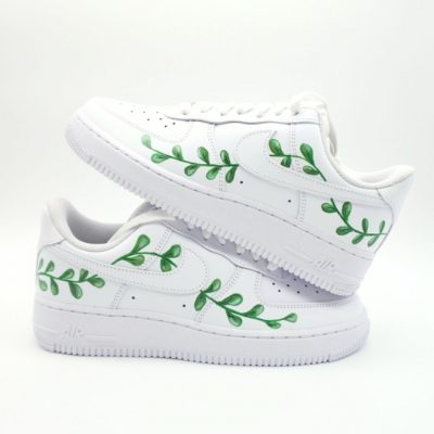 Paar weiße Nike Air Force 1 Custom Sneaker mit handgemalten grünen Blätterzweigen, dezentes Eukalyptus-Motiv für die Kommunion auf beiden Schuhen