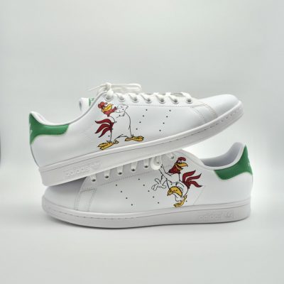 Weiße Adidas Stan Smith Schuhe mit grünem Akzent und Foghorn Leghorn Motiv auf der Seite.