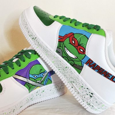 Weiße Sneakers mit grünen Akzenten und Ninja Turtle Motiven von Raphael und Leonardo.
