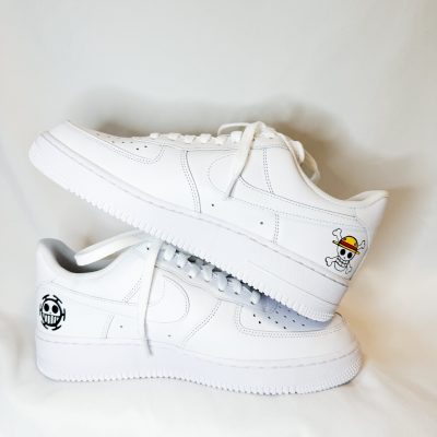 Weiße Sneakers mit einem One Piece Logo auf der Seite und einem bunten Aufdruck auf der Ferse.