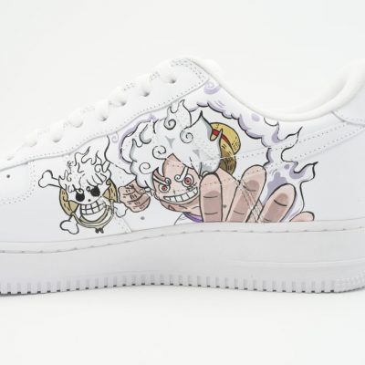 Nahaufnahme eines weißen Nike Air Force 1 mit handgemaltem Anime-Motiv des Charakters Ruffy in Gear 5 aus One Piece und kleinem Totenkopf-Detail an der Seite.