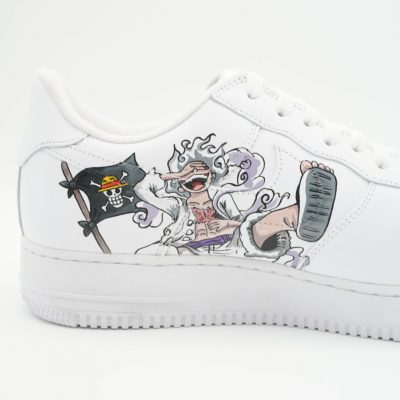 Nahaufnahme eines weißen Nike Air Force 1 mit handgemaltem One Piece Gear 5 Ruffy und schwarz-weißer Strohhut-Piratenflagge auf der Seitenfläche.
