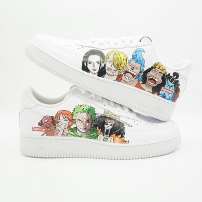 Zwei gestapelte weiße Nike Air Force 1 mit handgemalten One Piece Strohhut-Piraten Charakteren auf beiden Seiten und kleinem Supreme-Logo-Detail am Boden.