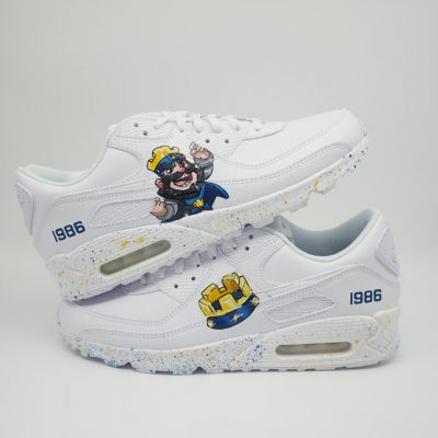 Paar weiße Nike Air Max Custom Sneaker mit Clash Royale Design, Königs- und Burg-Motive sowie Jahreszahl 1986, gestapelte Präsentation mit Farbspritzer-Sohle