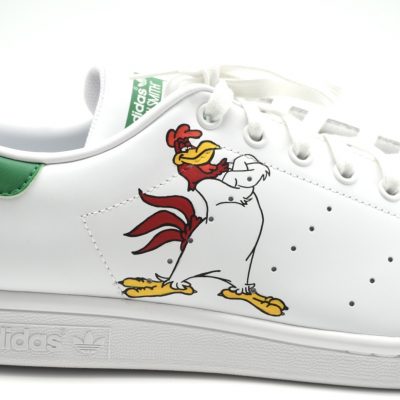 Weißer Adidas Stan Smith Custom Sneaker mit handgemaltem Foghorn Leghorn Motiv auf der Seite, grüne Fersenkappe und seitliche Nahaufnahme vor neutralem Hintergrund