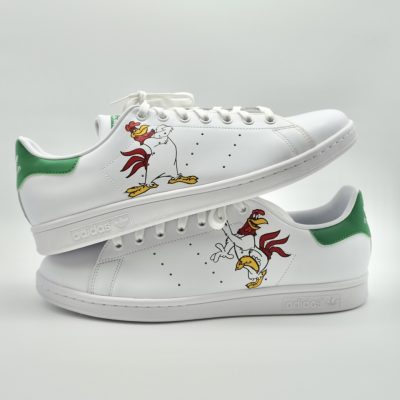 Paar weiße Adidas Stan Smith Custom Sneaker mit handgemaltem Foghorn Leghorn Motiv und grünen Fersenkappen, gestapelte Seitenansicht beider Schuhe vor neutralem Hintergrund