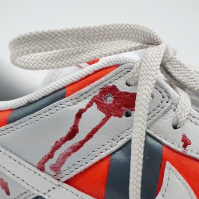 Detailansicht des Mittelfußbereichs eines Custom Sneakers mit Freddy Krueger Design, rot-graue Streifen mit Blutspritzer-Motiven und beigefarbenen Schnürsenkeln