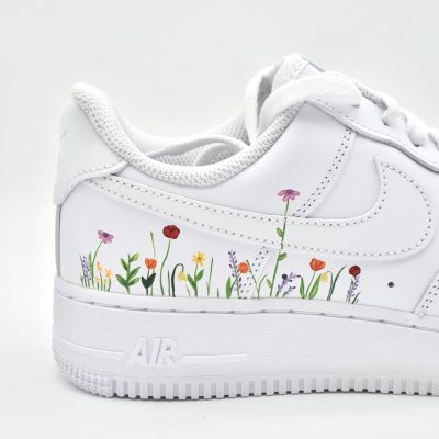 Nahaufnahme eines weißen Nike Air Force 1 mit handgemaltem Frühlingsblumen-Beet aus bunten Blumen wie Tulpen, Mohn und Glockenblumen an Sohle und Ferse.