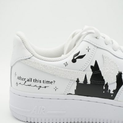 Zwei gestapelte weiße Nike Air Force 1 mit handgemalter schwarzer Hogwarts Silhouette, goldenem Schnatz, glitzernder Ferse und Schriftzug 'After all this time? Always'.