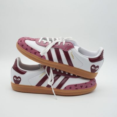 Paar weiße Adidas Samba Custom Sneaker mit dunkelrot-rosa Farbgebung, kleine Herz-Motive auf der rosa Wildlederfläche und Comic-Augen-Herz auf der Fersenkappe