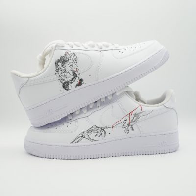 Paar weiße Nike Air Force 1 Custom Sneaker mit Kunst-Schlangen-Motiv in Schwarz-Weiß, dezente Linienzeichnungen und kleine rote Akzente auf den Außenseiten