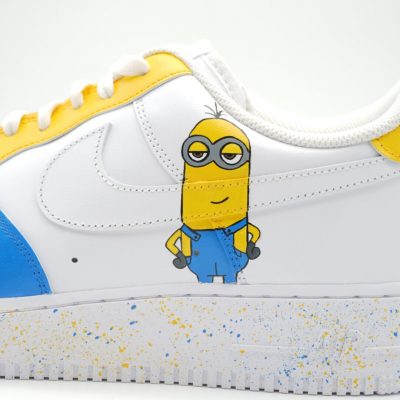 Nahaufnahme eines weißen Nike Air Force 1 mit handgemaltem großen Minion in blauer Latzhose, gelb-blauer Fersenkappe und blauen Akzenten am Mittelfeld.