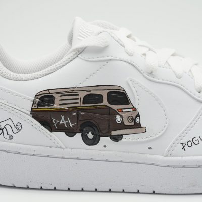 Nahaufnahme eines weißen Sneakers mit handgemaltem braunen VW Bus, 'P4L' Schriftzug und kleinem 'POGUE' Detail an der Seite im Outer Banks Serien-Design.