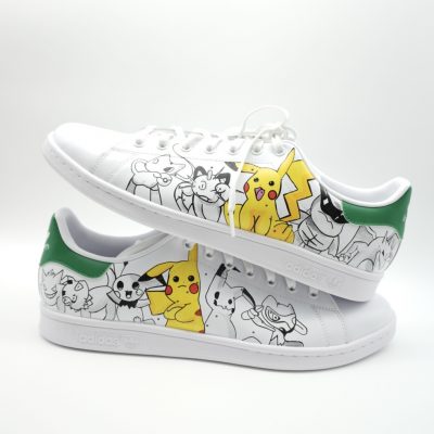 Paar weiße Adidas Stan Smith Custom Sneaker mit Pokémon-Design, Pikachu in Gelb und weitere Pokémon-Motive als Outline-Zeichnungen, gestapelte Seitenansicht