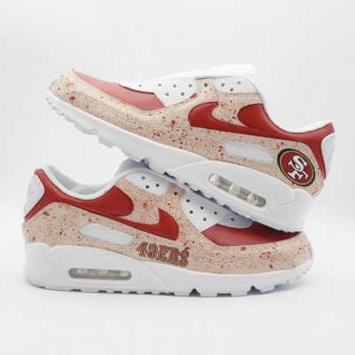 Paar weiße Nike Air Max Custom Sneaker mit San Francisco 49ers Design, rote Akzente Schriftzug 49ers Vereinslogo und beigefarbene Farbspritzer auf der Außenseite