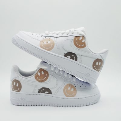 Paar weiße Nike Air Force 1 Custom Sneaker mit Smiley-Faces in Braun- und Beigetönen, verschiedene lächelnde Gesichter über die gesamte Außenseite verteilt