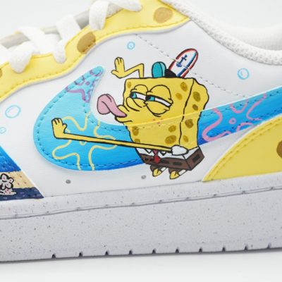 Weißer Custom Sneaker mit handgemaltem SpongeBob-Motiv und gelb-blauen Swoosh-Elementen, Nahaufnahme der Außenseite mit Wassermuster und Korallen vor neutralem Hintergrund