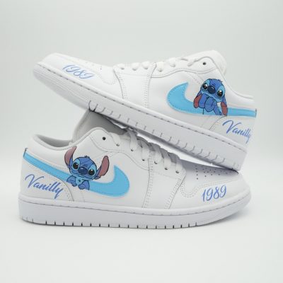 Zwei gestapelte weiße Air Jordan 1 Low mit blauem Stitch Motiv am Swoosh, Aufschrift 'Vanilly' und Datum '1989' an den Fersen im verspielten Disney-Design.