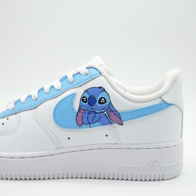 Weißer Nike Air Force 1 Custom Sneaker mit handgemaltem Stitch-Motiv auf hellblauem Swoosh, seitliche Außenansicht des linken Schuhs vor neutralem Hintergrund