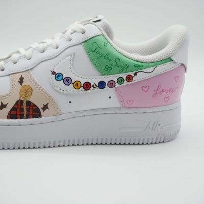 Detailansicht eines weißen Nike Air Force 1 Custom Sneaker mit Taylor Swift Eras Tour Design, Freundschaftsarmband-Motiv und grüne Fersenkappe mit Schriftzug Taylor Swift