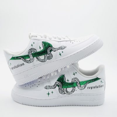 Paar weiße Nike Air Force 1 Custom Sneaker mit Taylor Swift Reputation Design, grüne Glitzer-Schlangen-Motive und Reputation-Schriftzug auf beiden Schuhen