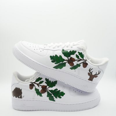 Paar weiße Nike Air Force 1 Custom Sneaker mit Wald-Motiv, Eichenblätter und Eicheln in Grün und Braun sowie Hirsch- und Wildschwein-Silhouetten auf den Seiten
